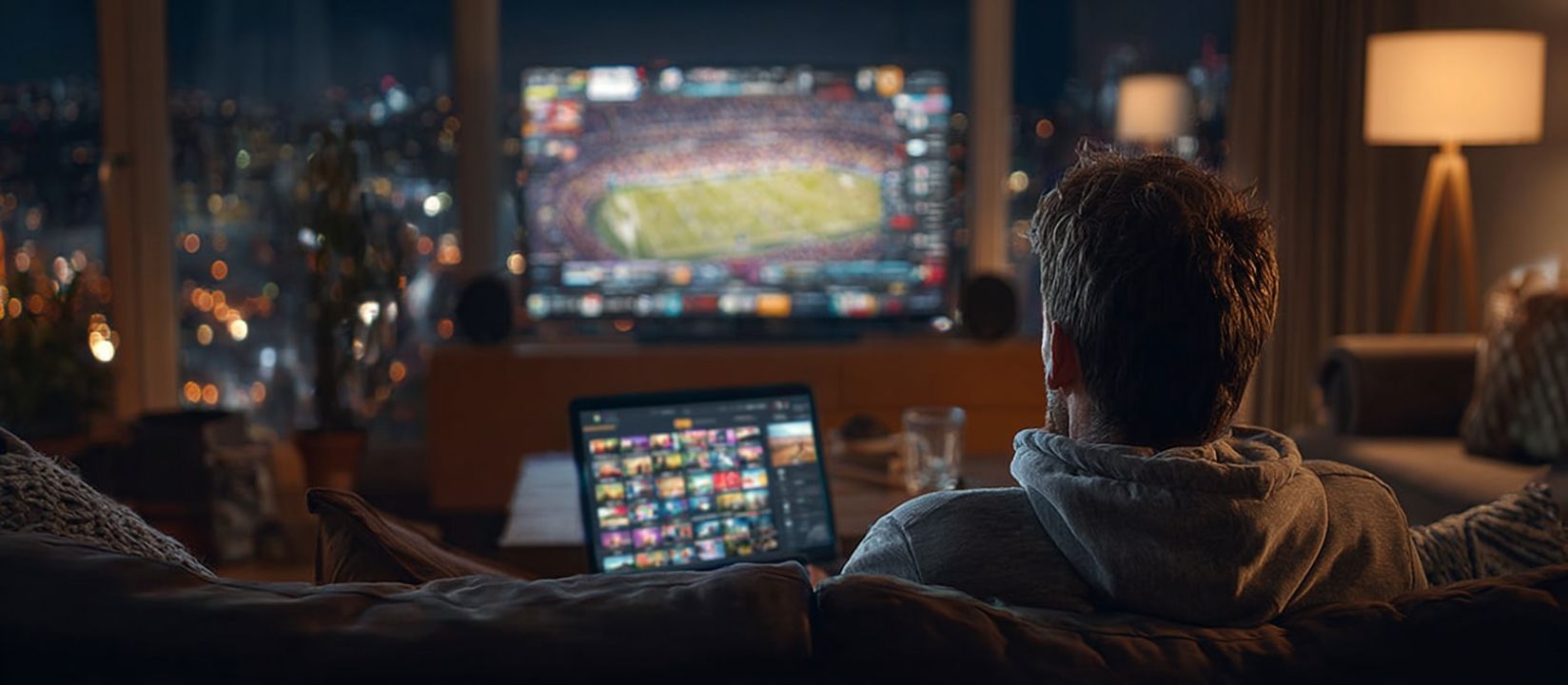 Bet on live sports today with WW555 Casino Man watching live football match on TV with laptop open for betting, representing sports betting at WW555 Casino